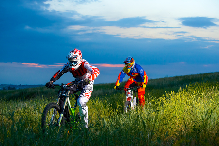 ZAPORIZHZHYA, UKRAINE - JUNE 16, 2015: Two Fully Equipped Professional Downhill Cyclists Riding Bikes on the Summer Trail. Extreme Sportsのeditorial素材
