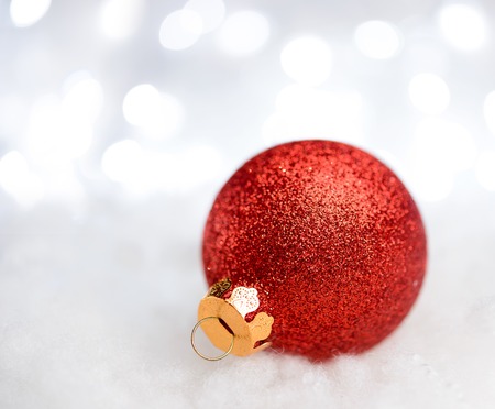 Christmas Decoration with Red Ball in the Snow on the Blurred Background with Holiday Lights. Greeting Card with Space for Your Textの写真素材
