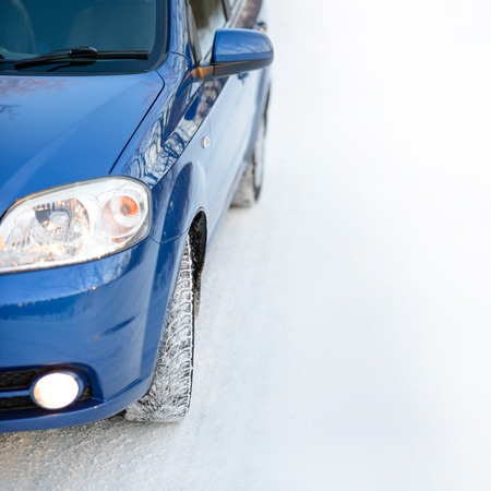 Blue Car with Winter Tires on the Snowy Road. Drive Safe Concept with Space for Text.の写真素材