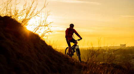 Silhouette of Enduro Cyclist Riding the Mountain Bike on the Rocky Trail at Sunset. Active Lifestyle...