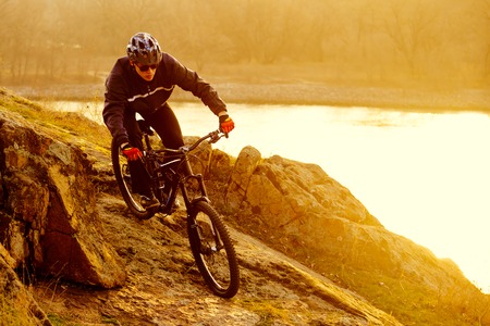 Enduro Cyclist Riding the Mountain Bike Down Beautiful Rocky Trail. Extreme Sport Concept. Free Space for Text.の写真素材