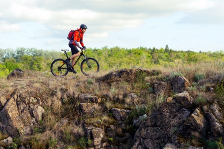 Cyclist in Red Jacket Riding the Mountain Bike on the Beautiful Rock. Extreme Sport Conceptの写真素材