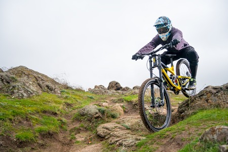 Professional Cyclist Riding Mountain Bike Down the Rocky Hill. Extreme Sport and Enduro Biking Concept.の写真素材
