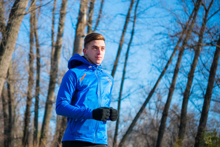 Young Sports Man Running in the Park in Cold Sunny Autumn Morning. Healthy Lifestyle and Sport...