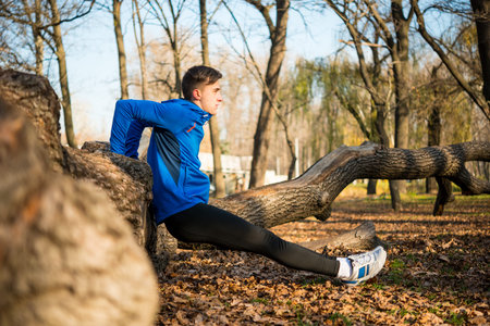 Male Runner Doing Push Up on the Log in the Park in Sunny Autumn Morning. Healthy Lifestyle and...