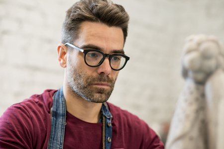 Portrait of Ceramist Dressed in an Apron Working on Clay Sculpture in Bright Ceramic Workshop.の写真素材