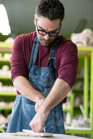 Ceramist Dressed in an Apron Working with Raw Clay in Bright Ceramic Workshop.