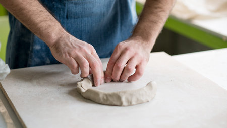 Ceramist Dressed in an Apron Working with Raw Clay in Bright Ceramic Workshop.