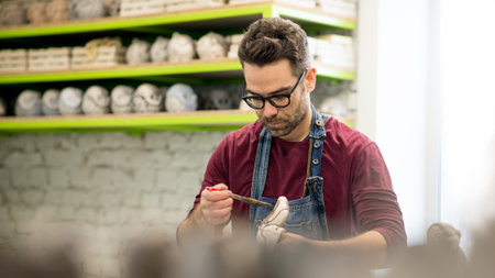 Portrait of Ceramist Dressed in an Apron Working on Clay Sculpture in Bright Ceramic Workshop.