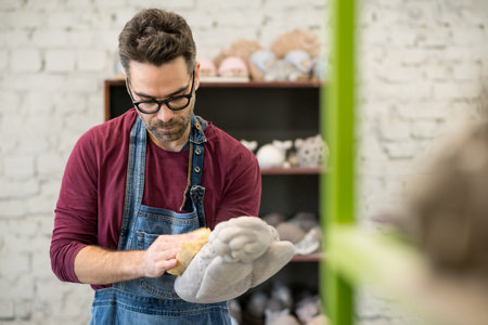 Portrait of Ceramist Dressed in an Apron Working on Clay Sculpture in Bright Ceramic Workshop.
