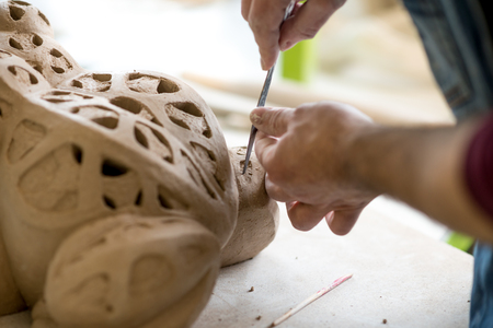 Ceramist Dressed in an Apron Sculpting Statue from Raw Clay in the Bright Ceramic Workshop.の写真素材