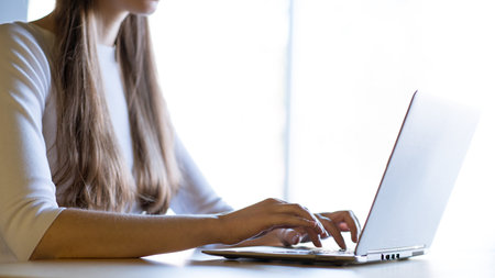 Close up Image of Woman Hands Typing on the Laptop Keyboard in Front of Big Bright Window.