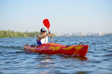 Young Professional Woman Kayaker Paddling Kayak on the River under Bright Morning Sun. Sport and Active Lifestyle Conceptの写真素材