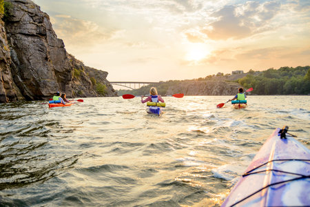 Friends Paddling Kayaks on the Beautiful River or Lake near High Rock under the Dramatic Evening Sky...