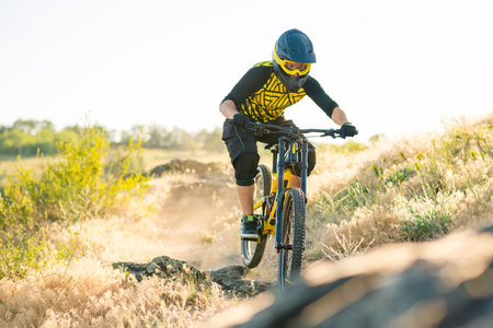 Cyclist Riding the Mountain Bike on the Summer Rocky Trail at the Evening. Extreme Sport and Enduro...