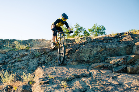 Cyclist Riding the Mountain Bike on the Summer Rocky Trail at the Evening. Extreme Sport and Enduro Cycling Concept.の写真素材