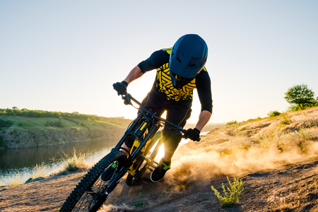 Cyclist Riding the Mountain Bike on the Summer Rocky Trail at the Evening. Extreme Sport and Enduro Cycling Concept.の写真素材