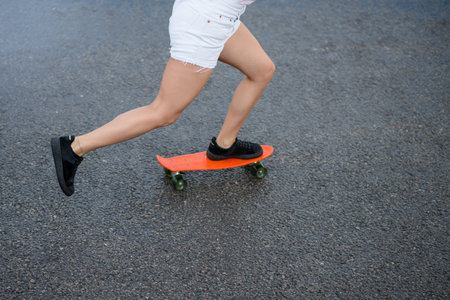 Young Beautiful Blonde Girl Riding Orange Skateboard on the Bridge