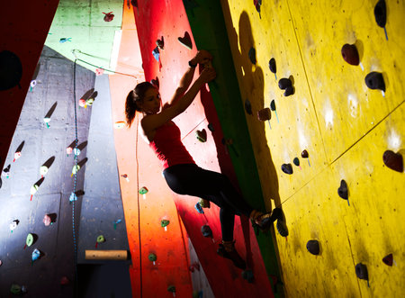 Young Active Woman Bouldering on the Colorful Artificial Rock in Climbing Gym. Extreme Sport and...