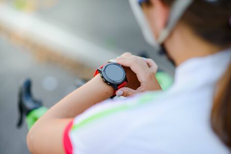 Young Woman with Road Bicycle Using Smartwatch at Sunset. Closeup of Hand with Fitness Tracker. Training Sports Concept.の写真素材