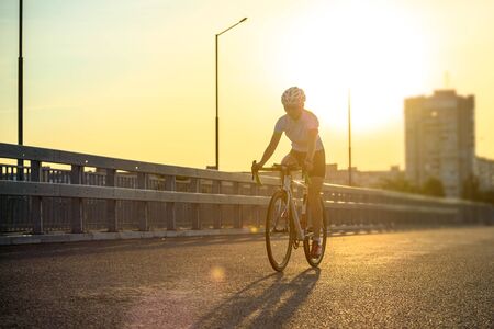 Young Woman Riding Road Bicycle on Free Street in the City at Sunset. Healthy Lifestyle and Sport Concept.の写真素材