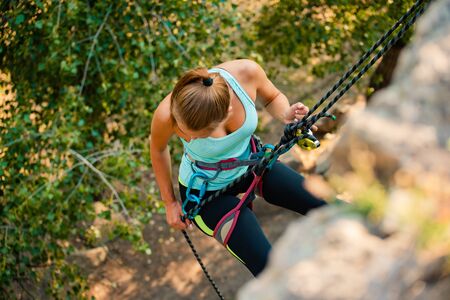 Beautiful Woman Climbing on the Rock in the Mountains. Adventure and Extreme Sport Conceptの写真素材