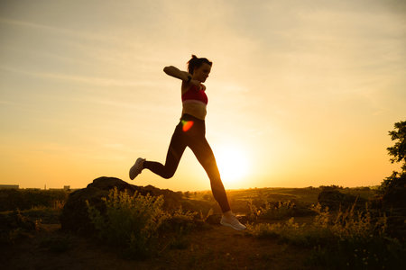 Young Beautiful Woman Running on the Mountain Trail at Hot Summer Sunset. Sport and Active Lifestyle Concept.の写真素材