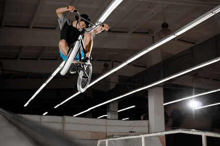 Young BMX Rider Doing Extreme Tricks on the Bike in the Skatepark Indoor. Healthy and Active...