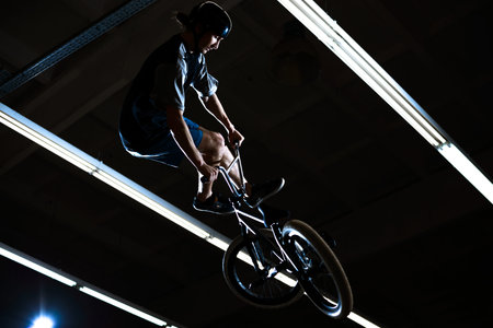 BMX Rider Doing Extreme Tricks on the Bike in the Dark Skatepark Indoor. Healthy and Active...