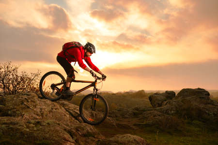 Cyclist in Red Riding Bike on the Summer Rocky Trail at Sunset. Extreme Sport and Enduro Biking Concept.の写真素材