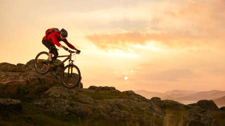 Cyclist in Red Riding Bike on the Summer Rocky Trail at Sunset. Extreme Sport and Enduro Biking Concept.の写真素材
