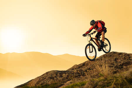 Cyclist Riding Bike on the Rocky Trail in the Summer Mountains at Sunset. Extreme Sport and Enduro Cycling Concept.の写真素材