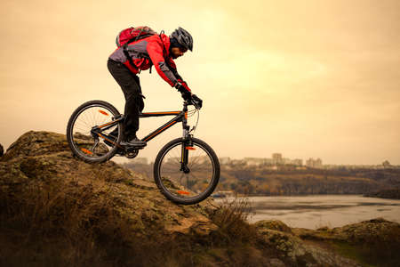Cyclist Riding the Mountain Bike on the Rocky Trail at Cold Autumn Evening. Extreme Sport and Enduro Cycling Concept.の写真素材