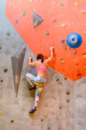 Young Woman Climber Bouldering in Climbing Gym. Extreme Sport and Indoor Climbing Conceptの写真素材
