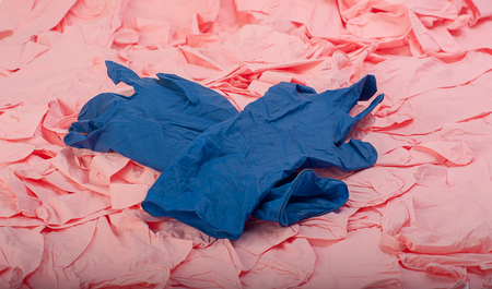 New blue latex medical glove on background of a lot of pink rubber glovesの写真素材