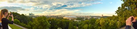 Moscow, Russia - July 10, 2017: A young girl photographing the Moscow cityscape on a smartphoneのeditorial素材