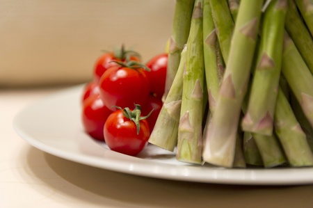 Green asparagus and red tomatoes on the plateの写真素材