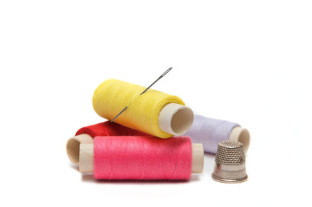 Color threads with needle and thimble on the white background