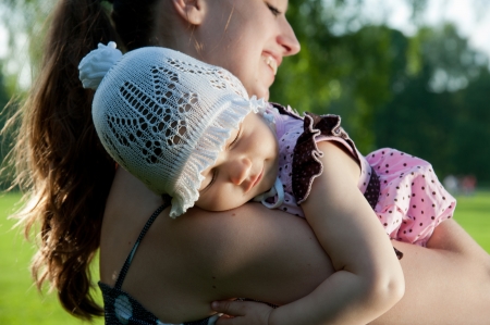 Woman holds child on shoulder in the parkの写真素材