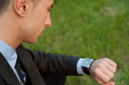 Man checking the time on the background of parkの写真素材