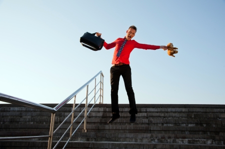 Happy businessman jumping near the stairs on the background of blue skyの写真素材
