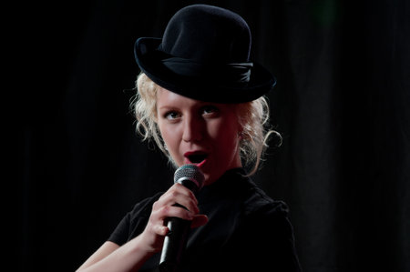 Pretty woman singing in microphone over the black background