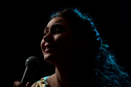 Pretty woman singing in microphone over the black backgroundの写真素材