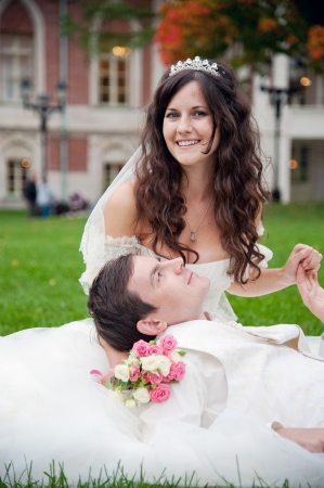 Groom and bride relaxing on a grass in the parkの写真素材