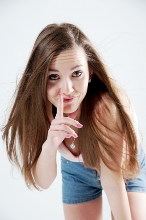 Portrait of young beautiful smiling woman with finger on her lipsの写真素材