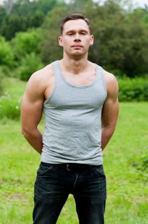 Man in a t-shirt stands on the grass in the park の写真素材