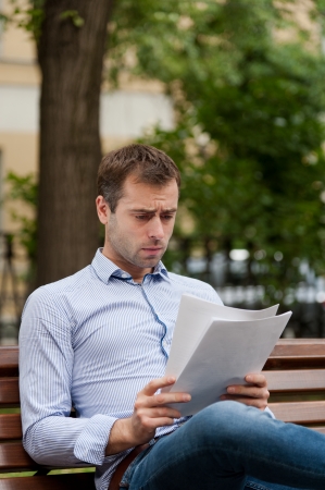 Man sits on the bench and read documents in the public gardenの写真素材