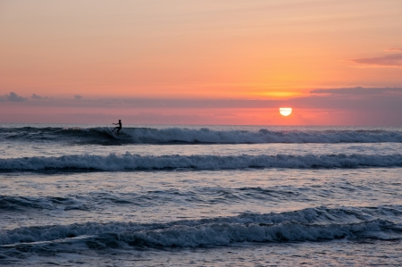 Beautiful ocean with surfer at the orange sunsetの写真素材