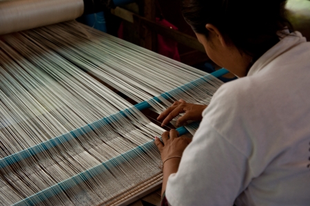 SIEM REAP, CAMBODIA - July 18, 2013  A weaver adjusts the silk cloth on her loom, July 18, 2013, near Siem Reap, Cambodiaのeditorial素材
