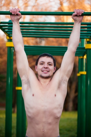 Closeup of young strong athlete doing pull-up on horizontal barの写真素材